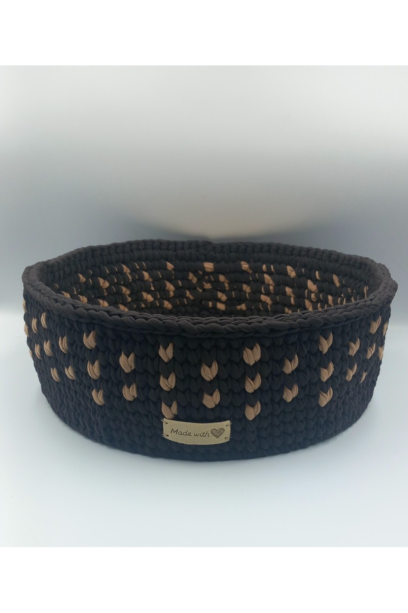 Στρογγυλό χειροποίητο καλάθι σε καφέ-μπεζ χρωματισμούς.